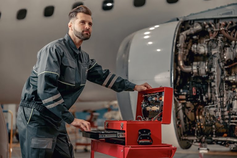 Bearded man airline mechanic working in aircraft hangar