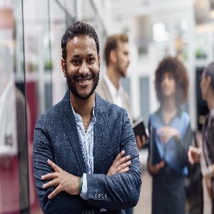 Portrait of indian businessman standing in modern office on colleagues background