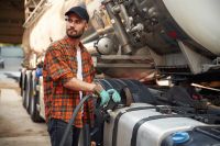 Young truck driver in casual clothes is refueling the vehicle